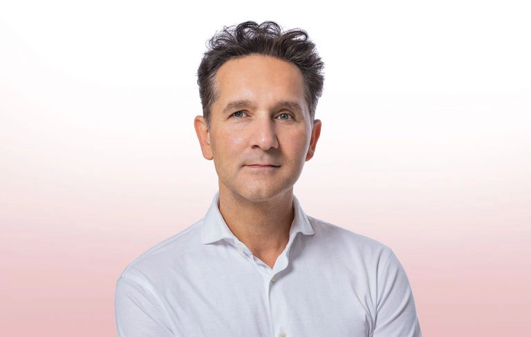 Dr. med. Engin Osmanoglou, Kardiologe in Berlin-Zehlendorf, im weißen Hemd vor hellem Hintergrund