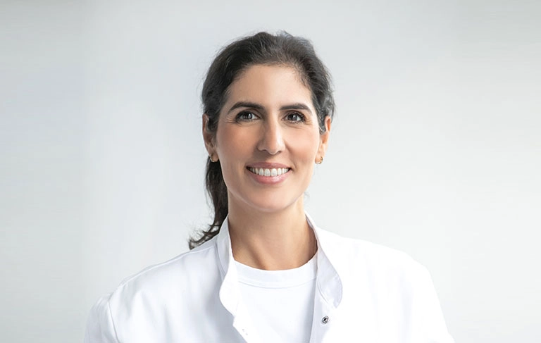Yasemin Yesilöz, Fachärztin für Innere Medizin und Kardiologie, lächelnd im weißen Arztkittel